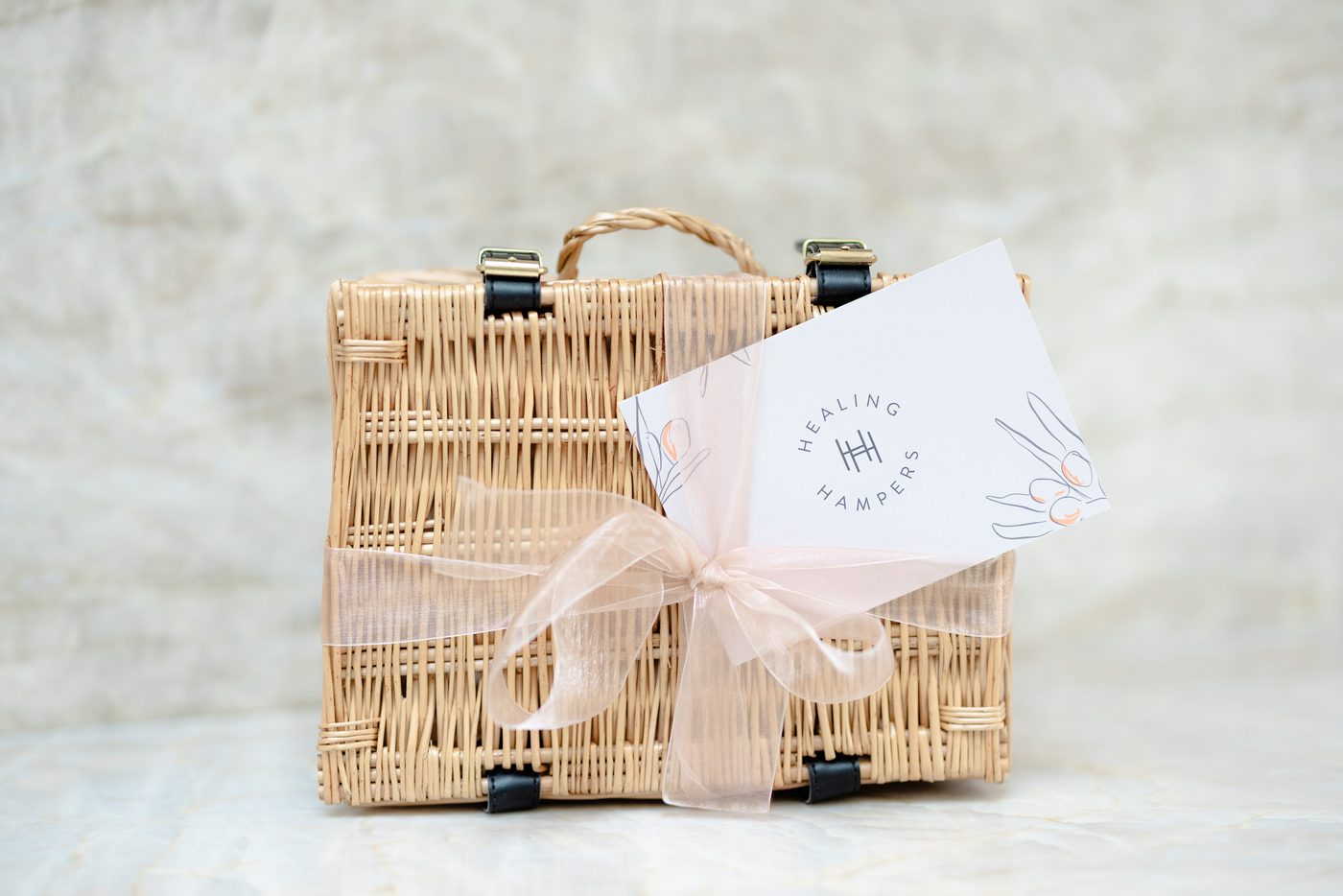 A Healing Hampers wicker basket with a blush ribbon and a handwritten card